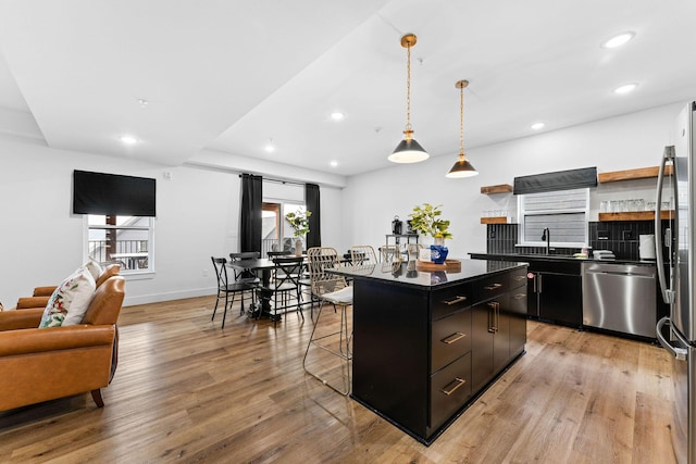 400 Poolside Pass, Hollister, MO 65672 - kitchen featuring appliances with stainless steel finishes, dark cabinetry, a kitchen breakfast bar, dark countertops, and light wood-style flooring