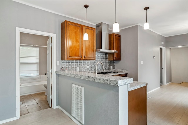 318 W Olive St, Aurora, MO 65605 - kitchen featuring wall chimney exhaust hood, light wood-style flooring, brown cabinetry, backsplash, and hanging light fixtures