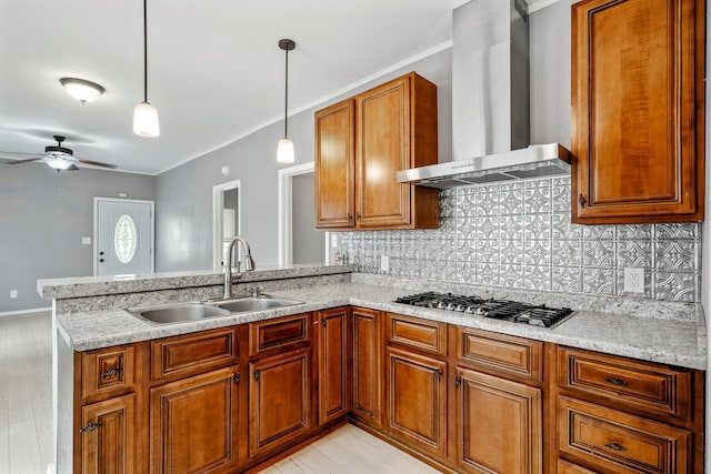 318 W Olive St, Aurora, MO 65605 - kitchen with a sink, wall chimney range hood, a peninsula, stainless steel gas cooktop, and brown cabinets