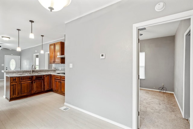 318 W Olive St, Aurora, MO 65605 - kitchen with brown cabinetry, a peninsula, decorative backsplash, decorative light fixtures, and a sink