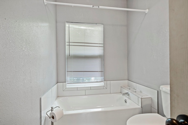 318 W Olive St, Aurora, MO 65605 - bathroom featuring a bath, a textured wall, and toilet