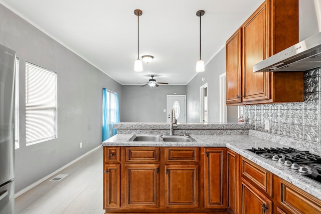 318 W Olive St, Aurora, MO 65605 - kitchen featuring wall chimney range hood, a sink, a peninsula, a ceiling fan, and stainless steel gas cooktop