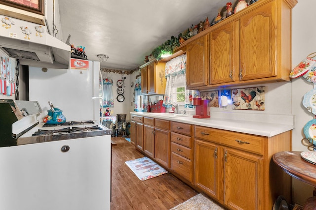 2140 N Crutcher Ave, Springfield, MO 65803 - kitchen featuring wood finished floors, under cabinet range hood, brown cabinetry, and light countertops