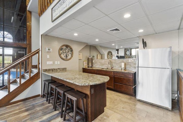 234 Sunset Cv Unit 107, Branson, MO 65616 - kitchen featuring freestanding refrigerator, a sink, recessed lighting, a breakfast bar area, and decorative backsplash