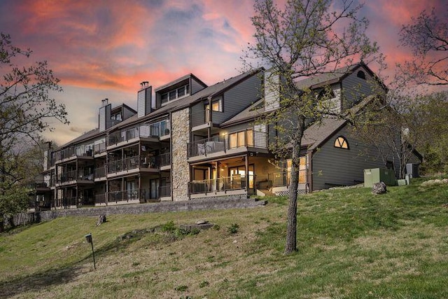234 Sunset Cv Unit 107, Branson, MO 65616 - rear view of property featuring a yard, a balcony, a chimney, and stone siding