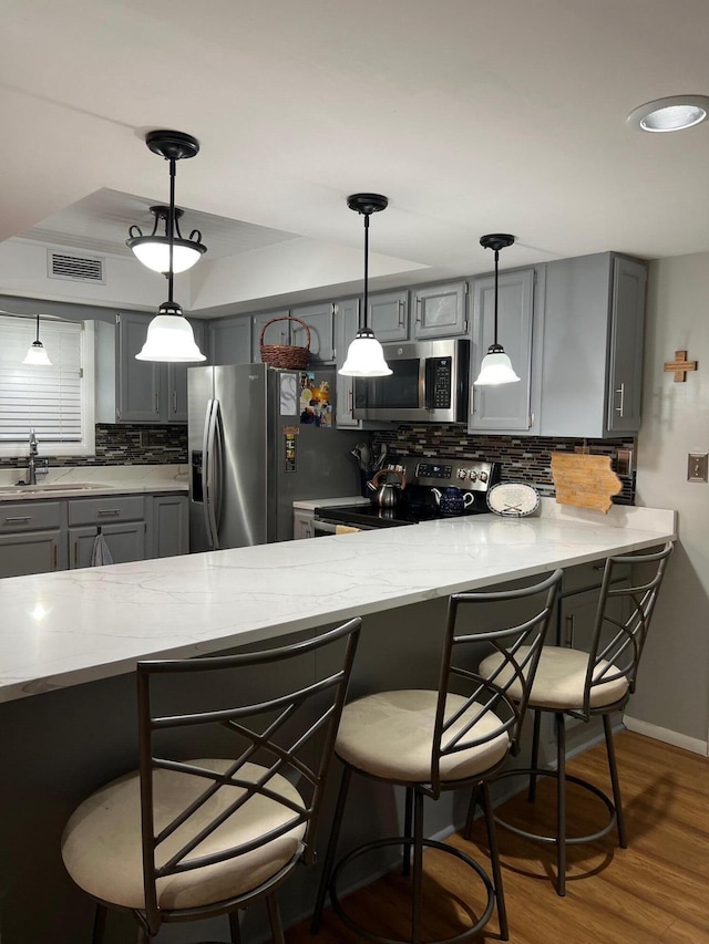 234 Sunset Cv Unit 107, Branson, MO 65616 - kitchen featuring stainless steel appliances, gray cabinetry, a sink, backsplash, and a kitchen breakfast bar