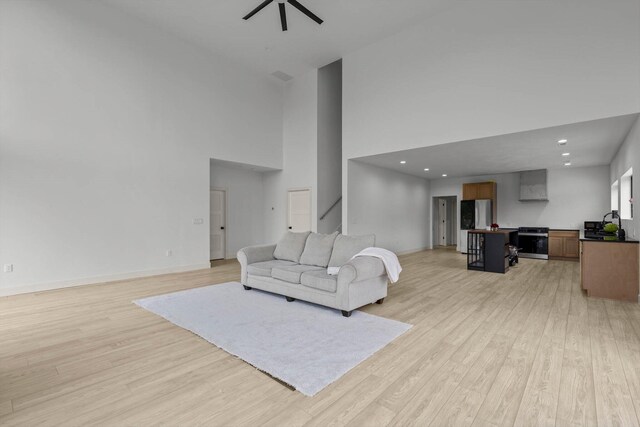 176 Shooting Star Ln, Nixa, MO 65714 - living area with light wood-style floors, a towering ceiling, ceiling fan, baseboards, and stairway