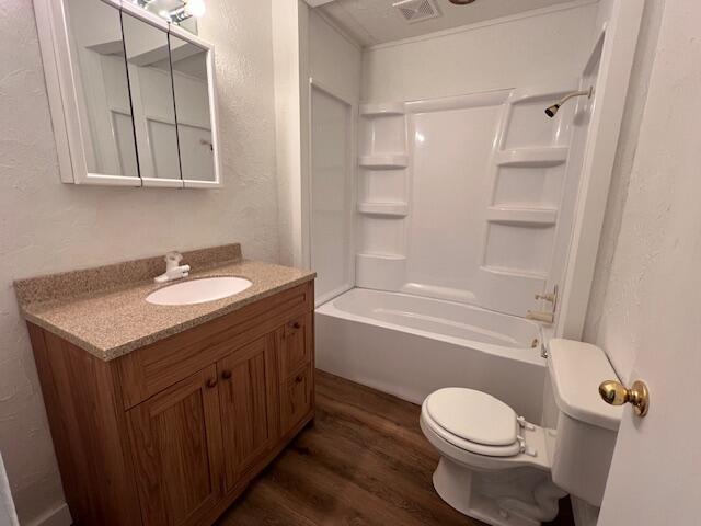 935 W Brower St, Springfield, MO 65802 - bathroom featuring wood finished floors, toilet, vanity, shower / tub combination, and a textured wall