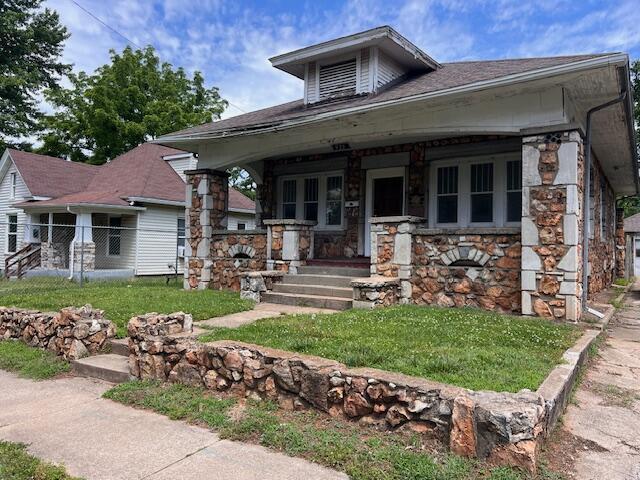 935 W Brower St, Springfield, MO 65802 - view of front facade featuring stone siding, a porch, and a front yard