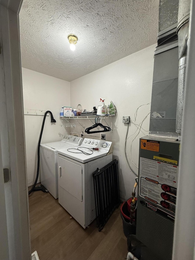 208 Justin St, Rogersville, MO 65742 - laundry room featuring light wood-style floors, washer and clothes dryer, a textured ceiling, and heating unit
