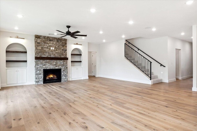4943 S Aaron Ave, Springfield, MO 65810 - unfurnished living room featuring a ceiling fan, built in features, light wood-type flooring, stairway, and a stone fireplace
