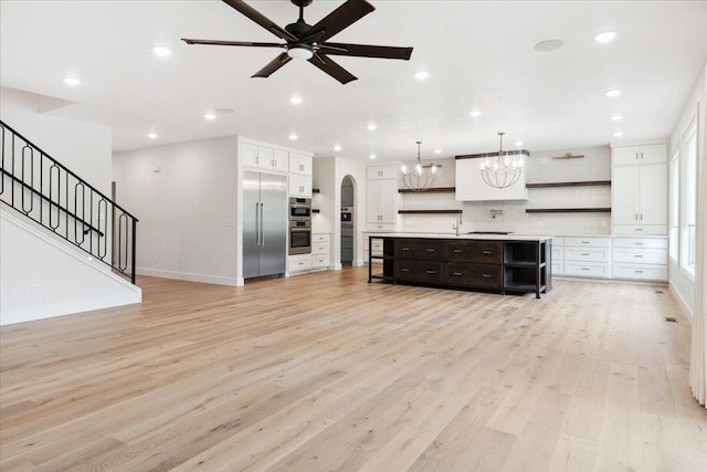 4943 S Aaron Ave, Springfield, MO 65810 - unfurnished living room with light wood-style flooring, arched walkways, a chandelier, a ceiling fan, and recessed lighting