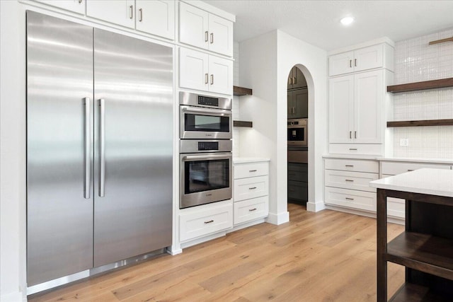 4943 S Aaron Ave, Springfield, MO 65810 - kitchen featuring appliances with stainless steel finishes, open shelves, light countertops, light wood-type flooring, and arched walkways