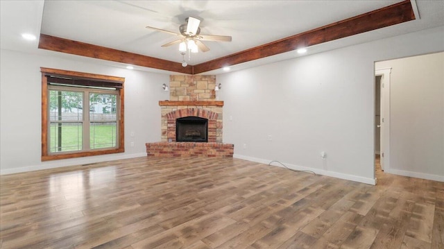 2606 Country Dr, Mountain Grove, MO 65711 - unfurnished living room featuring beamed ceiling, wood finished floors, a ceiling fan, a fireplace with raised hearth, and baseboards