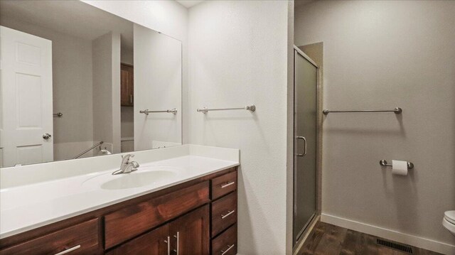 2606 Country Dr, Mountain Grove, MO 65711 - full bathroom featuring toilet, a shower stall, vanity, wood finished floors, and baseboards
