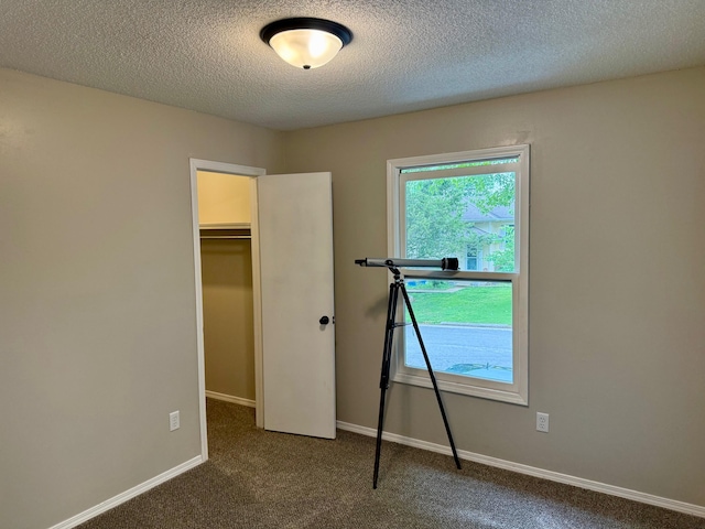 2004 S 16th St, Ozark, MO 65721 - unfurnished bedroom featuring carpet floors, a textured ceiling, a walk in closet, a closet, and baseboards