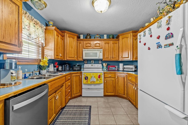 1640 E 541st Rd, Brighton, MO 65617 - kitchen featuring white appliances, brown cabinets, light tile patterned flooring, a sink, and a textured ceiling