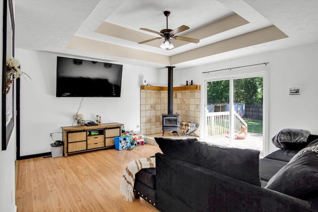 113 Holly Ridge Rd, Willard, MO 65781 - living area featuring a raised ceiling, a wood stove, wood finished floors, a ceiling fan, and baseboards