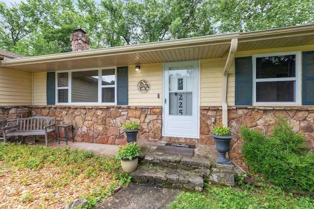 225 Elim St, Forsyth, MO 65653 - property entrance with stone siding, a chimney, and covered porch