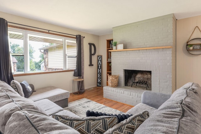 225 Elim St, Forsyth, MO 65653 - living room with wood finished floors, a brick fireplace, and baseboards