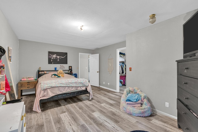 21371 Howell Rd, Mountain View, MO 65548 - bedroom with light wood-type flooring, baseboards, a textured ceiling, and a spacious closet
