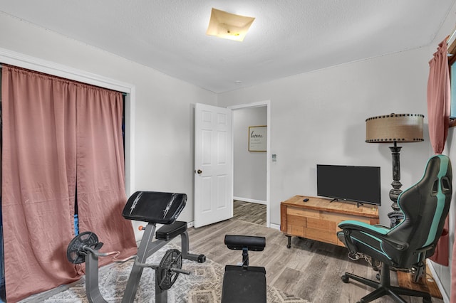 21371 Howell Rd, Mountain View, MO 65548 - workout room with wood finished floors, baseboards, and a textured ceiling