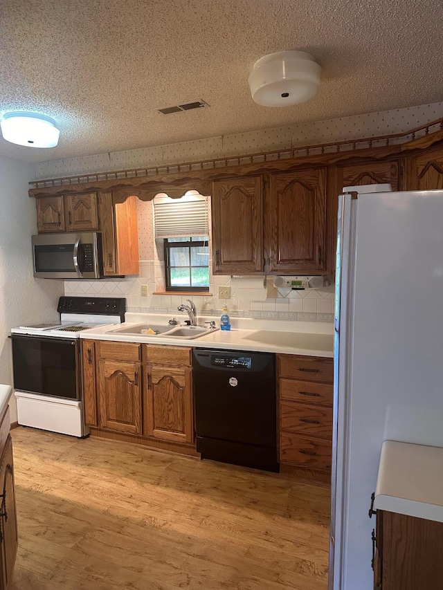 154A Scofield Ave, Forsyth, MO 65653 - kitchen featuring white appliances, brown cabinets, tasteful backsplash, light wood-type flooring, and a textured ceiling