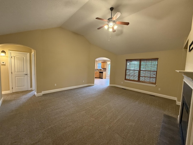 895 W Linwood Ave, Nixa, MO 65714 - unfurnished living room featuring arched walkways, ceiling fan, a fireplace with flush hearth, vaulted ceiling, and dark carpet