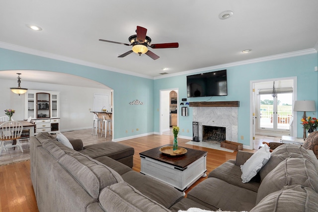 4402 Quail Run Rd, Ozark, MO 65721 - living room featuring arched walkways, ornamental molding, a ceiling fan, a high end fireplace, and light wood finished floors
