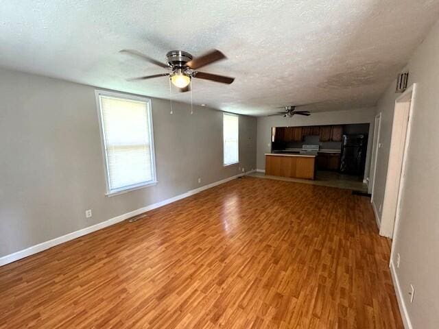 1211 W Calhoun St, Springfield, MO 65802 - unfurnished living room featuring a ceiling fan, baseboards, light wood finished floors, and a textured ceiling