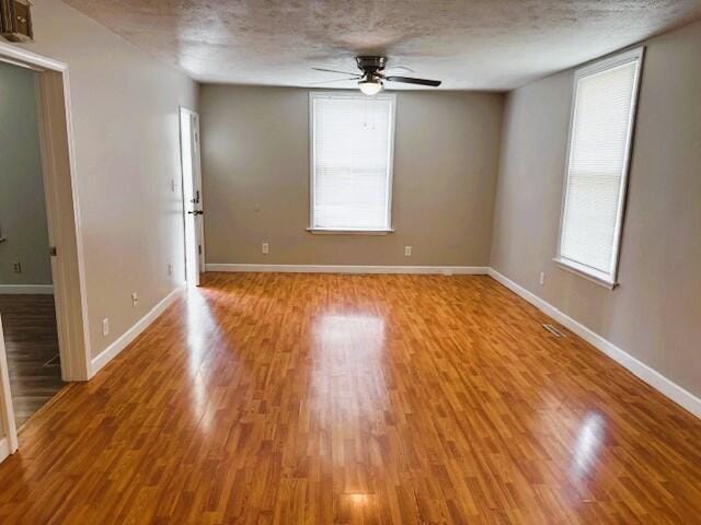 1211 W Calhoun St, Springfield, MO 65802 - unfurnished room with ceiling fan, light wood finished floors, baseboards, and a textured ceiling