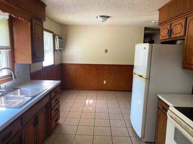 1208 Oak Ridge Dr, Aurora, MO 65605 - kitchen featuring a sink, wainscoting, healthy amount of natural light, a textured ceiling, and brown cabinetry
