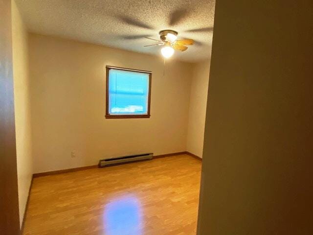 1208 Oak Ridge Dr, Aurora, MO 65605 - spare room with baseboard heating, a textured ceiling, a ceiling fan, and light wood-type flooring