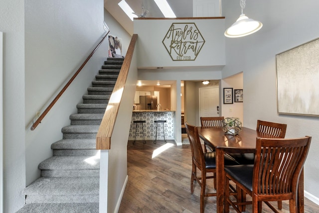 280 Wimbledon Dr Unit 9, Branson, MO 65616 - dining space with wood finished floors, stairway, a towering ceiling, baseboards, and a skylight