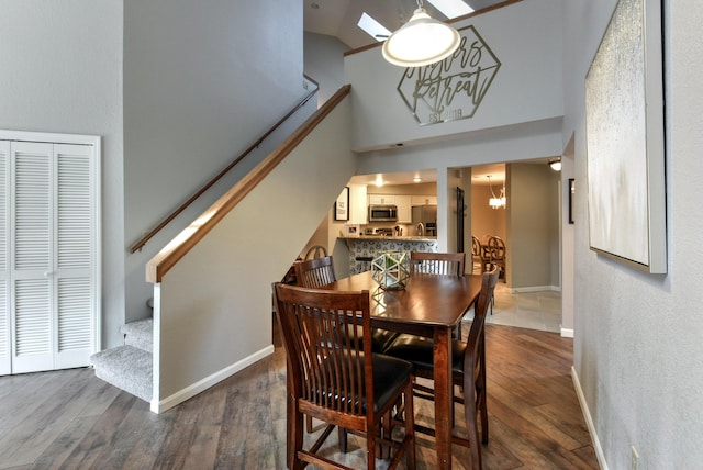 280 Wimbledon Dr Unit 9, Branson, MO 65616 - dining area featuring stairway, a towering ceiling, wood finished floors, a chandelier, and baseboards