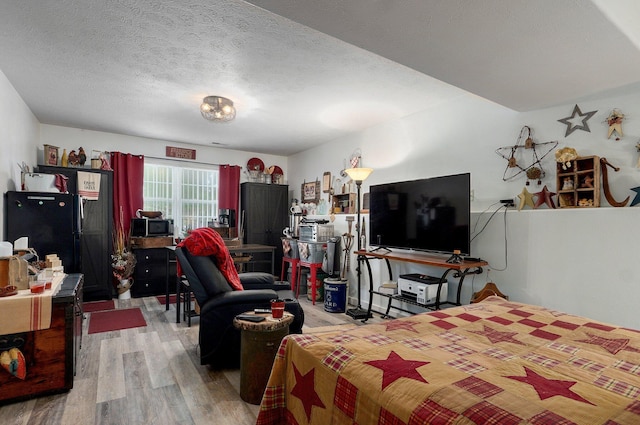 803 W Ridgecrest St, Ozark, MO 65721 - bedroom featuring light wood-style flooring, freestanding refrigerator, and a textured ceiling