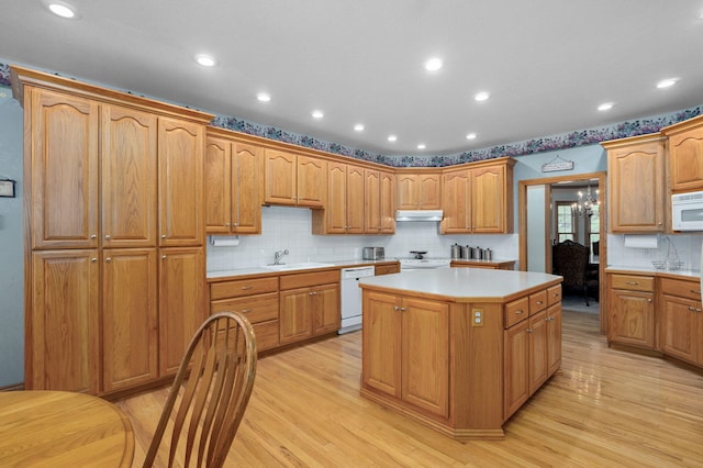 2411 W Dearborn St, Springfield, MO 65807 - kitchen with white appliances, a kitchen island, under cabinet range hood, light wood finished floors, and recessed lighting