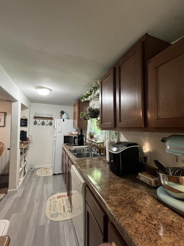 720 Highland St, Cabool, MO 65689 - kitchen featuring a sink, white dishwasher, stainless steel microwave, light wood-style flooring, and dark countertops