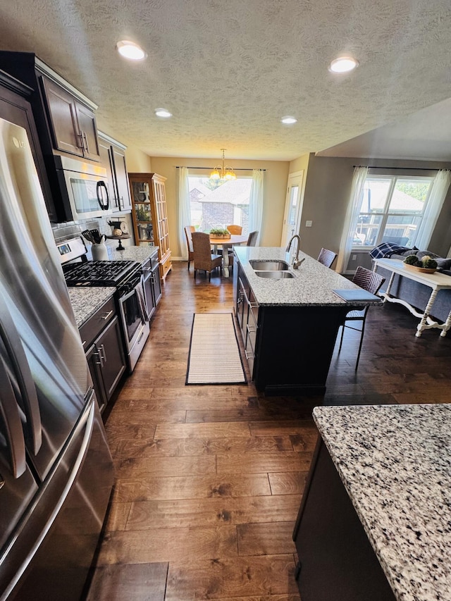 607 E Selby Dr, Nixa, MO 65714 - kitchen featuring appliances with stainless steel finishes, a textured ceiling, plenty of natural light, dark wood finished floors, and an island with sink