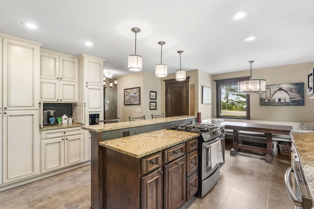 1029 Riverview Rd, Clever, MO 65631 - kitchen with stainless steel range with gas cooktop, cream cabinets, dark brown cabinetry, a kitchen island, and light stone countertops