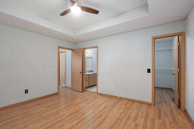 1651 S Mahn Ct, Springfield, MO 65802 - unfurnished bedroom with light wood-style floors, a walk in closet, a closet, a raised ceiling, and ensuite bathroom