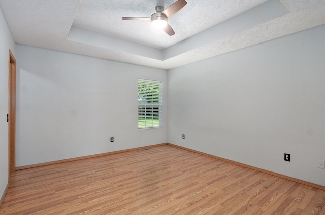 1651 S Mahn Ct, Springfield, MO 65802 - unfurnished room featuring a tray ceiling, light wood-style floors, ceiling fan, and a textured ceiling