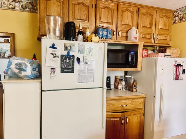 513 Meng St, Greenfield, MO 65661 - kitchen with freestanding refrigerator, black microwave, light countertops, and brown cabinetry