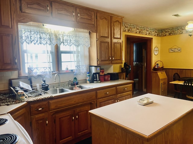 513 Meng St, Greenfield, MO 65661 - kitchen featuring light countertops, backsplash, a center island, brown cabinets, and wainscoting