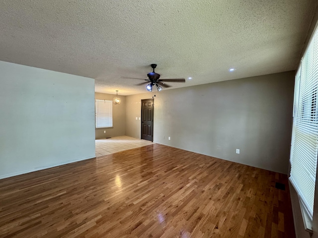 701 Barracuda Dr, Nixa, MO 65714 - empty room with wood finished floors, ceiling fan, a chandelier, and a textured ceiling