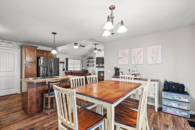 208 Dixie Ave, Clever, MO 65631 - dining space featuring dark wood-type flooring, a lit fireplace, a ceiling fan, vaulted ceiling, and a chandelier