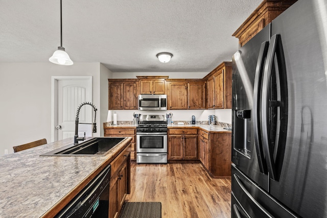208 Dixie Ave, Clever, MO 65631 - kitchen with appliances with stainless steel finishes, brown cabinets, light wood-type flooring, pendant lighting, and a textured ceiling