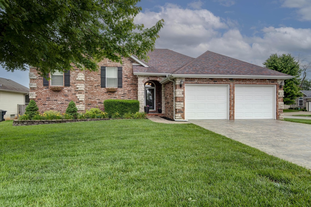 5229 S Carson St, Battlefield, MO 65619 - view of front of house with a garage, brick siding, a front yard, driveway, and roof with shingles