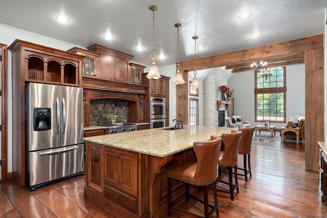 7607 N Angler Ln, Strafford, MO 65757 - kitchen featuring appliances with stainless steel finishes, dark wood-style floors, a large fireplace, light stone countertops, and glass insert cabinets