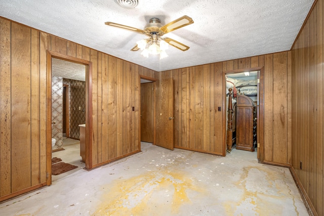 26307 Twin Rivers Dr, Shell Knob, MO 65747 - unfurnished bedroom with concrete flooring, wooden walls, a textured ceiling, ensuite bath, and ceiling fan